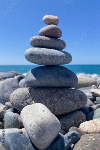 summer background. a beautiful pyramid of stones built on the seashore on a sunny day