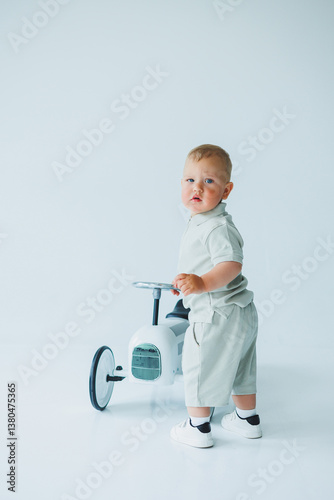 Obraz na płótnie A Cute Toddler Engaging in Play with a Charming White Tricycle Capturing Joyful and Heartwarming Moments in a Beautifully Minimalist Studio Setting Filled with Simple Details and Soft Lighting w salonie