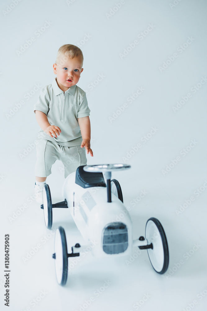 An absolutely adorable toddler is having a wonderful time playing on a stylish toy car within a bright and cheerful studio environment, filled with light and color to stimulate creativity and joy An absolutely adorable toddler is having a wonderful time playing on a stylish toy car within a bright and cheerful studio environment, filled with light and color to stimulate creativity and joy