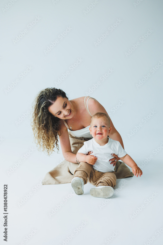 This image captures a truly joyful moment between a loving mother and her adorable child in a bright studio setting, showcasing their deep bond and the delightful interaction filled with warmth