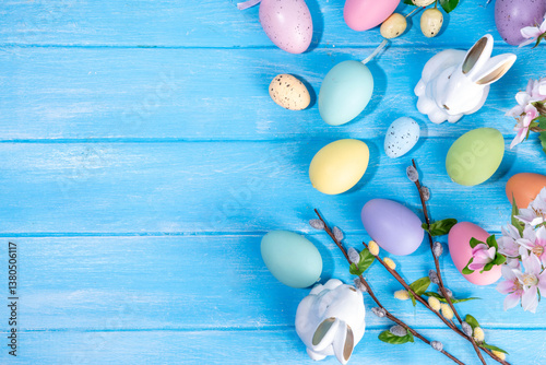 Spring Easter holiday top view flat lay background with eggs, bunny rabbits and spring flowers. Bright colorful greeting card background with copy space.