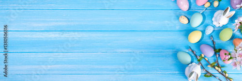 Spring Easter holiday top view flat lay background with eggs, bunny rabbits and spring flowers. Bright colorful greeting card background with copy space.