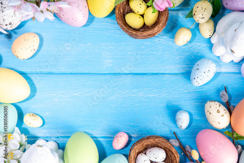Spring Easter holiday top view flat lay background with eggs, bunny rabbits and spring flowers. Bright colorful greeting card background with copy space.