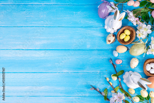 Spring Easter holiday top view flat lay background with eggs, bunny rabbits and spring flowers. Bright colorful greeting card background with copy space.