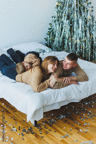 Obraz na płótnie A Joyful Family Gathering on a Cozy Bed Amidst Beautiful Christmas Decor, Creating a Warm and Festive Atmosphere Overflowing with Happiness and Love for the Holiday Season, Perfect for Togetherness w salonie