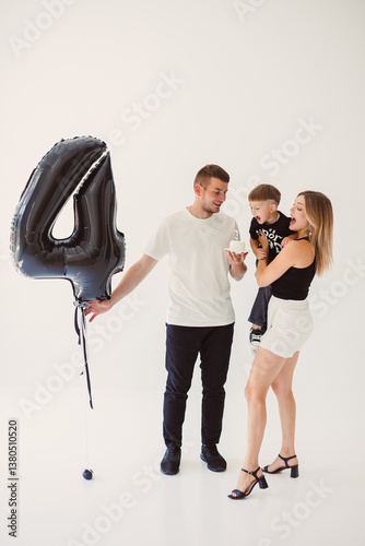 A joyful and happy family is seen celebrating a very special occasion together, surrounded by a large, colorful balloon shaped like the number four, symbolizing this moment of fun and love