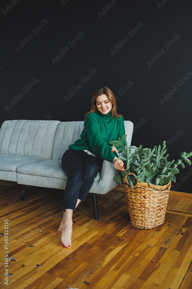 A woman sits on a chic sofa, arranging greenery into a woven basket to create a cozy atmosphere that reflects her inner peace, joy, artistic expression, and appreciation for beauty