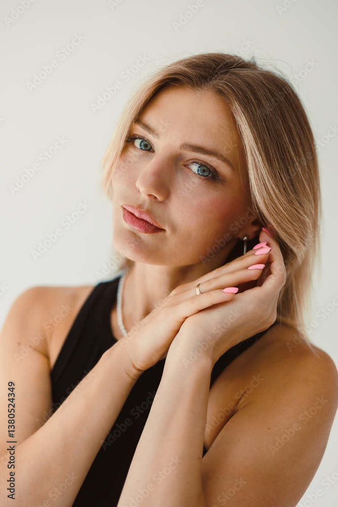 A stylish young woman is posing elegantly against a backdrop that enhances her light makeup and is beautifully complemented by her attractive accessories, showcasing her confidence and glamour