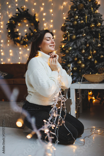 Obraz na płótnie Cute girl in New Year's locations in a cozy living room. Woman at home for the new year. w salonie