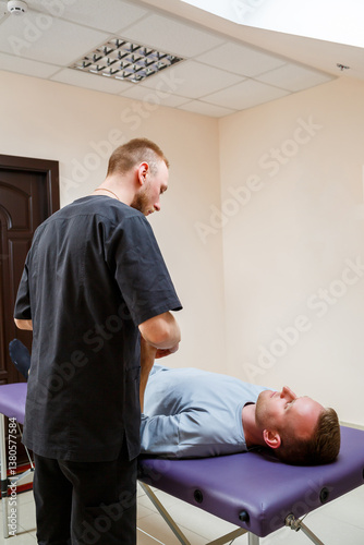 Obraz na płótnie A therapist is currently providing treatment to a patient who is lying on an examination table within a professional medical office setting, which embodies a sense of comfort and healing w salonie