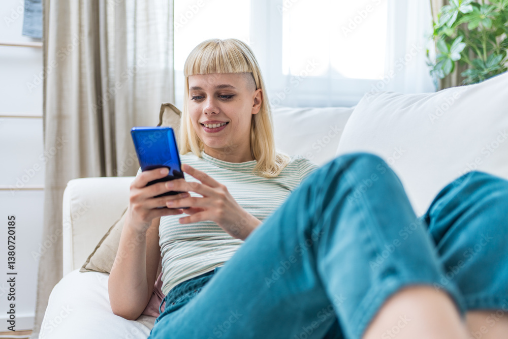 Smiling woman looking at smart phone screen, sitting on couch, enjoying leisure time with mobile device at home, happy young female chatting in social network or surfing internet, shopping online Smiling woman looking at smart phone screen, sitting on couch, enjoying leisure time with mobile device at home, happy young female chatting in social network or surfing internet, shopping online