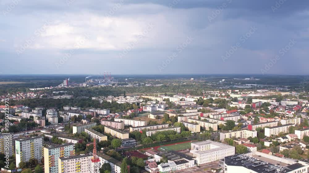 Drone view of urban city's buildings with green trees and football pitch under stunning cloudy sky Drone view of urban city's buildings with green trees and football pitch under stunning cloudy sky
