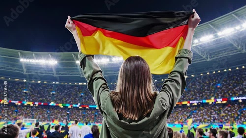 Enthusiastic german fan celebrating with flag in packed stadium at night