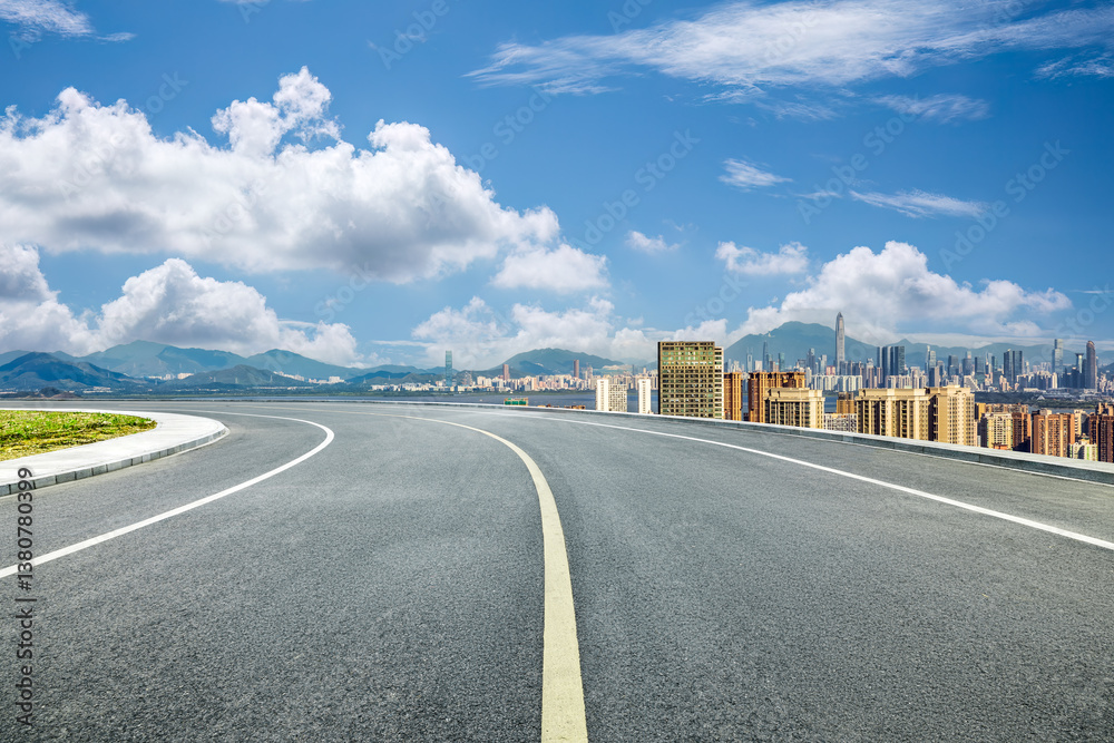 Empty asphalt road leading to Shenzhen cityscape with building and mountain range in the background. Empty asphalt road leading to Shenzhen cityscape with building and mountain range in the background.
