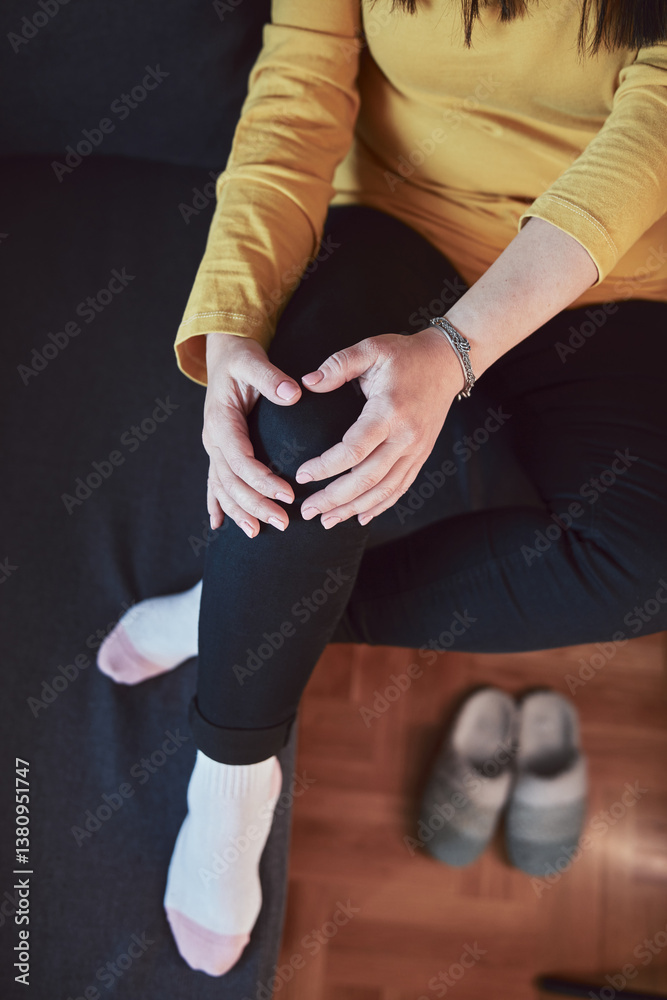 Woman with painful knee and leg injury at home.