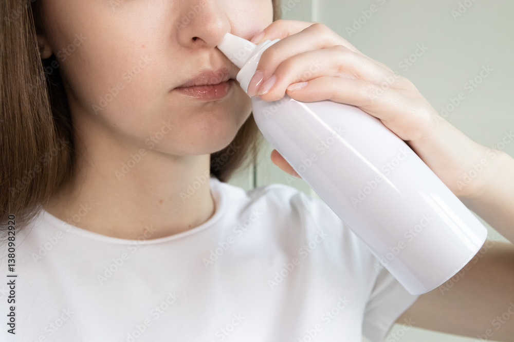 Young woman using saline irrigation spray to rinse her nose for alleviating allergies, colds, runny nose and nasal dryness. Young woman using saline irrigation spray to rinse her nose for alleviating allergies, colds, runny nose and nasal dryness.