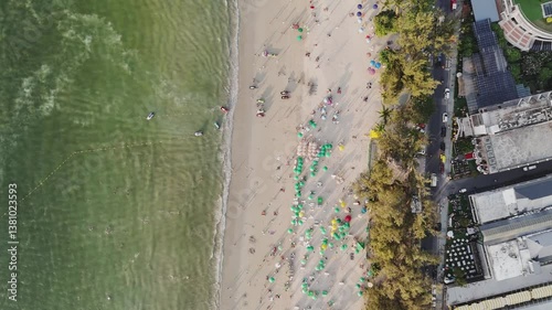 Beachgoers enjoying a sunny day at the shoreline coastal beach aerial view vibrant atmosphere relaxation focused