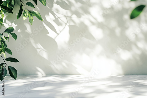 Empty marble stone table top with a blurred, abstract background of nature tree leaf shadows and a white wall for product display montage, a contemporary minimal concept