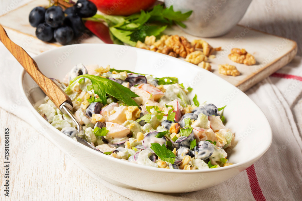 Waldorf salad with apples, celery, grapes and walnuts, dressed with mayonnaise and sprinkled with parsley.