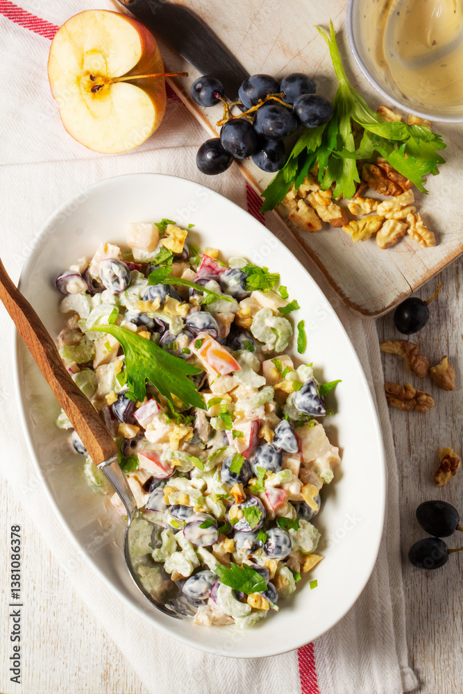 Waldorf salad with apples, celery, grapes and walnuts, dressed with mayonnaise and sprinkled with parsley.