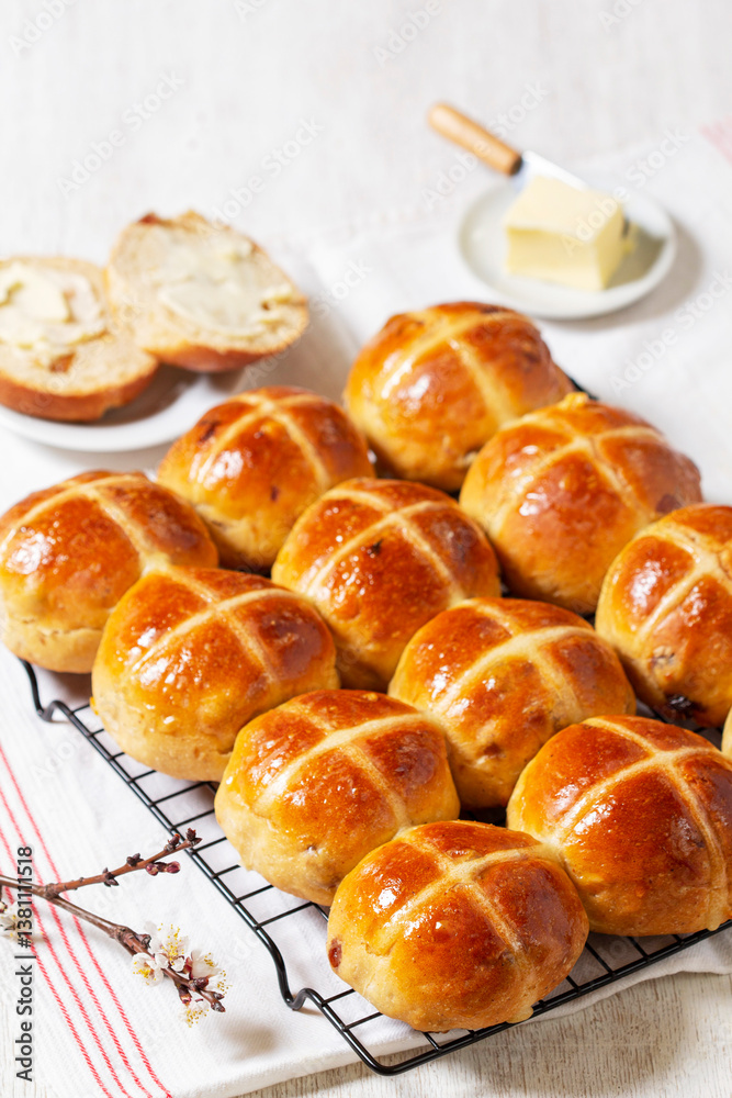 Hot cross buns served with butter and blossoming apricot branches.