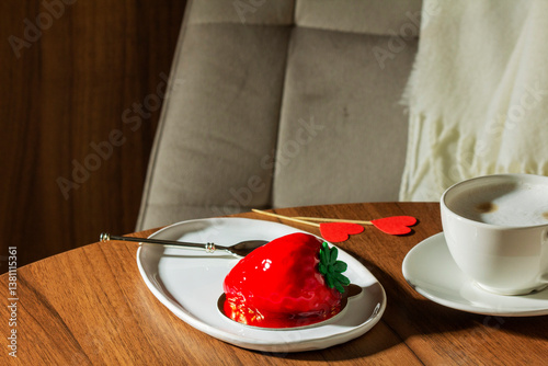 Obraz na płótnie Mousse cake with strawberry filling covered with mirror glaze and a cup of latte on a table in a cafe. w salonie