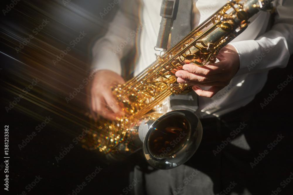 Obraz premium Close up shot on brass saxophone in hands of male musician playing jazz music on stage under bright spotlight, slow shutter effect, copy space