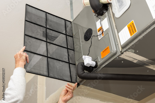 Replacing dirty central air conditioning  air filter.  HVAC repair technician performing maintenance on home indoor heating and cooling system. Air duct ventilation system maintenance for clean air. 
