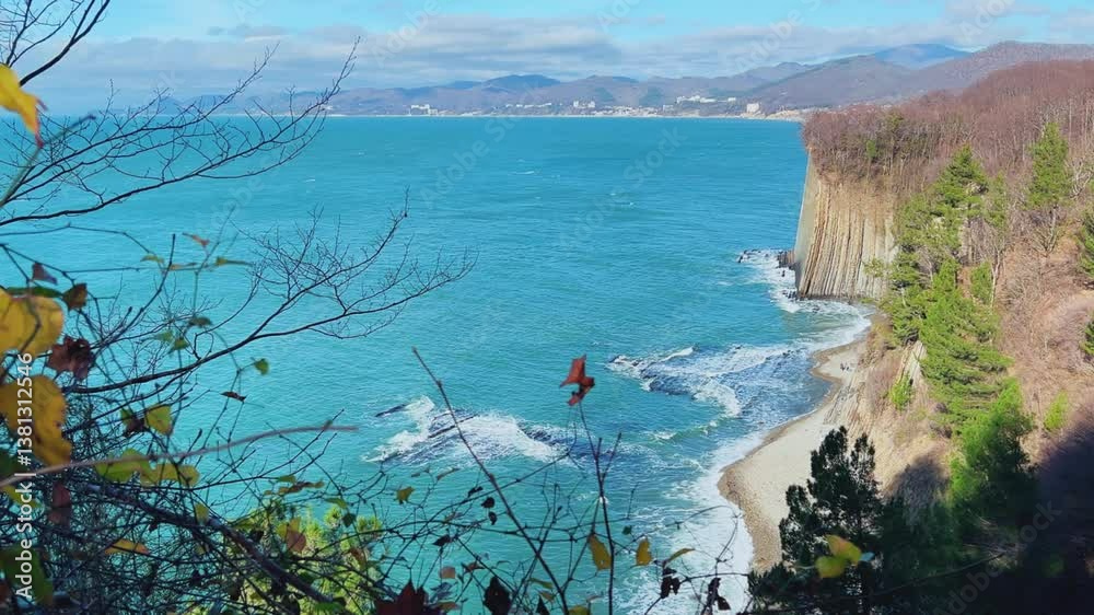 Panoramic view of the Black Sea coast from the mountain through the branches of trees. View of Kiselyov rock and rocky seashore in sunny weather. Russia, Tuapse. 4K