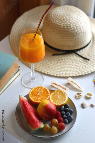Glass of cocktail, straw hat, sunglasses, books, fresh fruit, chocolate and accessories. Summer essentials on the table. Selective focus.