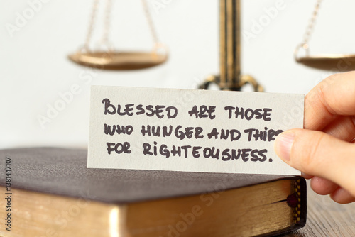 Christian blessing for righteousness, handwritten quote with holy bible book and balance scale in the background. Close-up. Justice and obedience to God Jesus Christ, biblical concept.