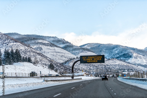 Vail, Colorado rocky mountains on Interstate 70 cars traffic to ski resorts snow with sign for icy conditions