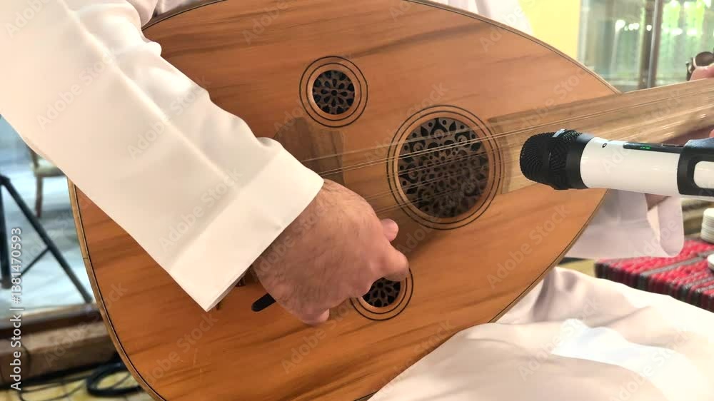 Oud instrument captures Arabic musical essence as fingers glide across carved wood, microphone nearby records every note for tourist seeking authentic culture and exclusive vacation tradition.