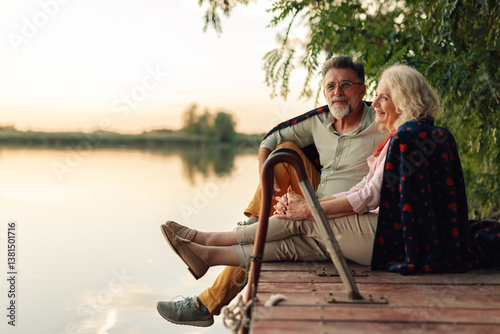 Εκτύπωση καμβά Senior couple relaxing by lake at sunset, enjoying retirement together