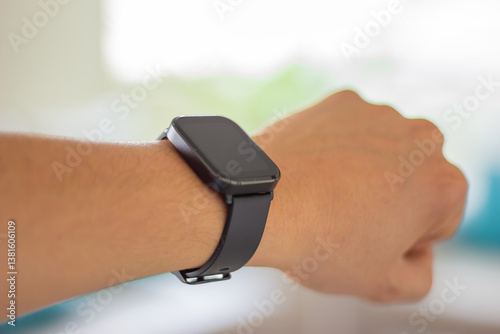 Close-up of a wrist wearing a black smartwatch with a blank screen. Concept of wearable technology, time management, and modern gadgets