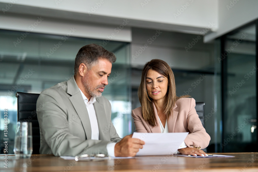 Fototapeta premium Two busy professional executives discussing financial accounting papers working together on b2b sales strategy in office. Mature business woman and man managers holding legal documents at meeting.