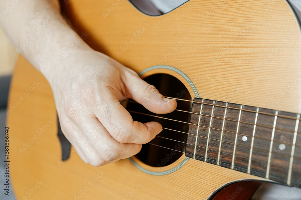 Fototapeta premium Close-up of a man's hands playing the guitar and strumming chords