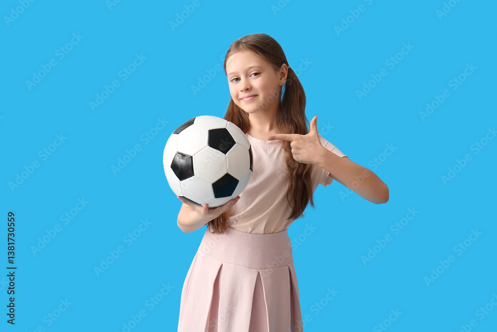 Little girl pointing at soccer ball on blue background