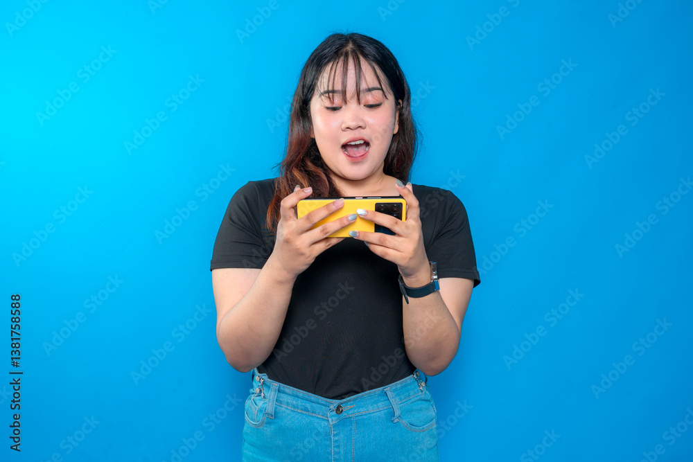 A young woman looks excitedly at her yellow smartphone with her mouth open, expressing surprise and engagement against a bright blue background. A young woman looks excitedly at her yellow smartphone with her mouth open, expressing surprise and engagement against a bright blue background.