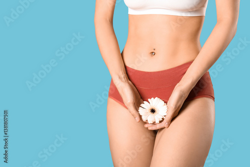 Young woman in panties with beautiful white flower on blue background