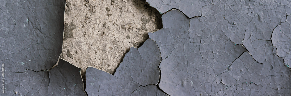 Peeling paint on the wall. Panorama of a concrete wall with old cracked flaking paint. Weathered rough painted surface with patterns of cracks and peeling. Wide panoramic texture for design background