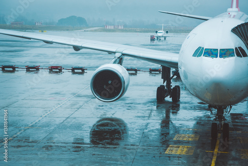 Billede på lærred Aircraft parked at airport apron under rain, delayed, cancelled or getting ready for departure under bad weather conditions