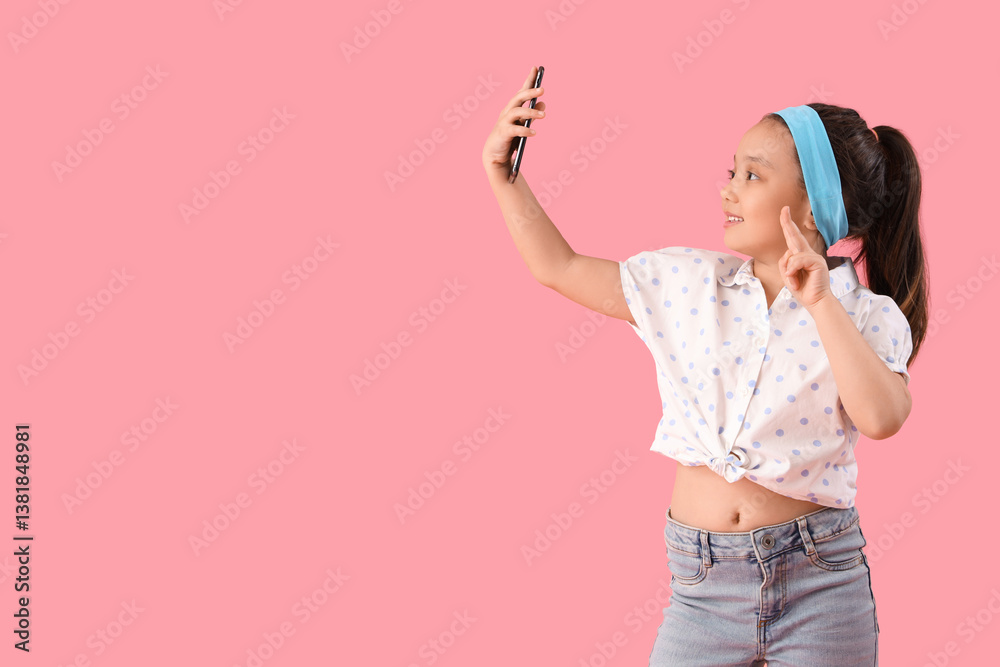 Portrait of fashionable little girl taking selfie on pink background