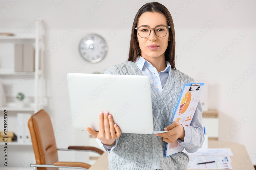 Young businesswoman with laptop and report in office Young businesswoman with laptop and report in office