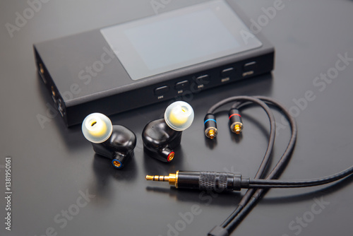 High-quality in-ear monitors with detachable cables, featuring black earpieces, ear tips, and a gold-plated 3.5mm jack. Ideal for audiophiles and musicians. Isolated on a sleek gray background