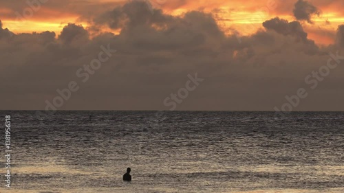 Adult male surfer swimming the Indian Ocean and waiting a wave at sunset time. Maldives. Slow motion video