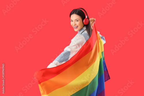 Beautiful young woman with rainbow flag on red background. LGBT concept