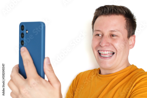 Happy man with braces taking a selfie with smartphone on white background