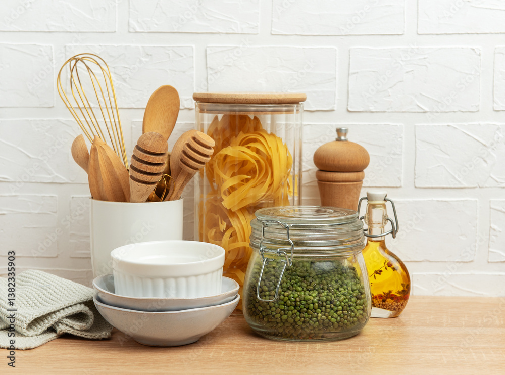 Kitchen utensils, pasta, mung beans, and oil creating a cozy culinary scene