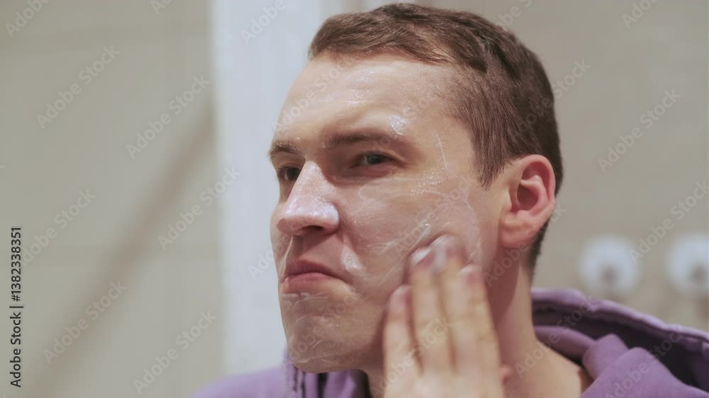 Man Applying Face Cream in Bathroom Mirror During Morning Routine for Skincare Man Applying Face Cream in Bathroom Mirror During Morning Routine for Skincare